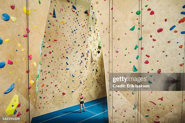 caucasian woman examining indoor rock wall - klimmuur stockfoto's en -beelden