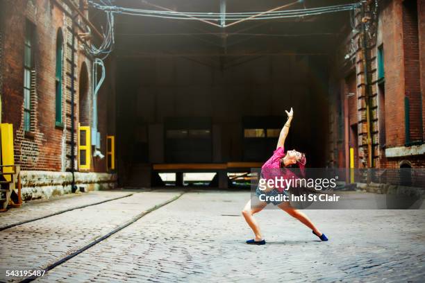 Caucasian woman dancing on cobblestone street