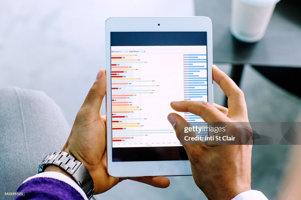 Mixed race businessman examining graph on digital tablet