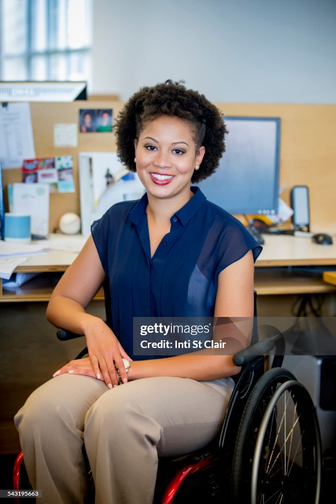 Mixed race businesswoman in wheelchair at office desk