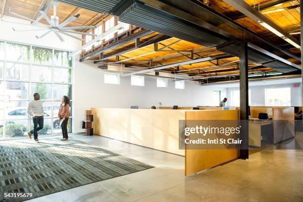 business people talking in office lobby - person standing far stockfoto's en -beelden