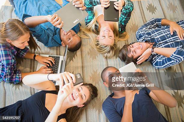 teenagers laying on floor using technology - alleen tieners stockfoto's en -beelden