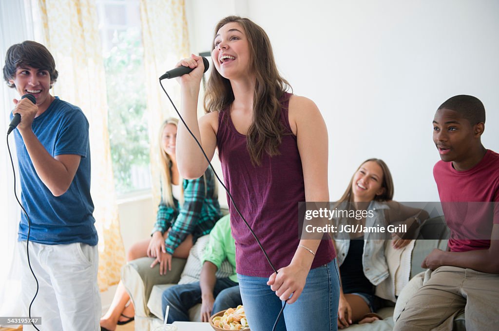 Teenagers singing karaoke at party
