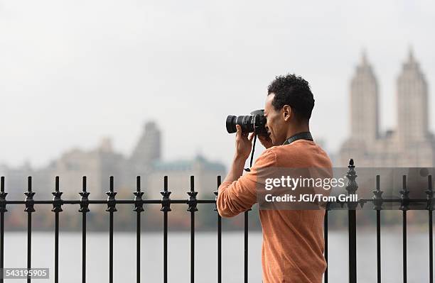 mixed race man taking photograph on urban waterfront - look away from camera stock pictures, royalty-free photos & images