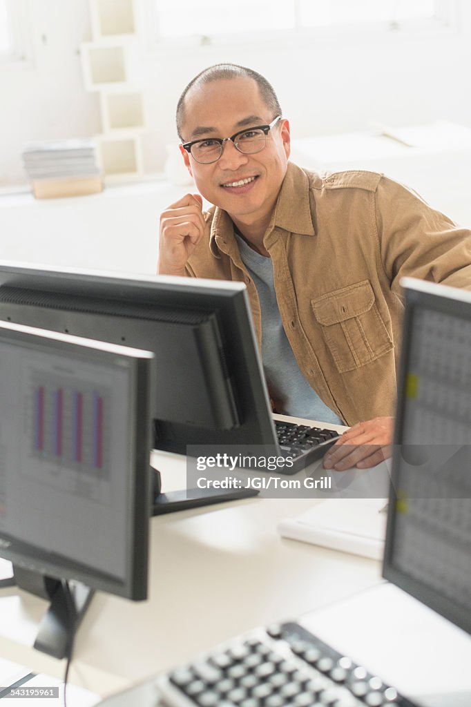 Korean businessman smiling at computer at office desk