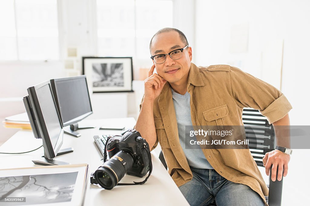 Korean photographer smiling at desk