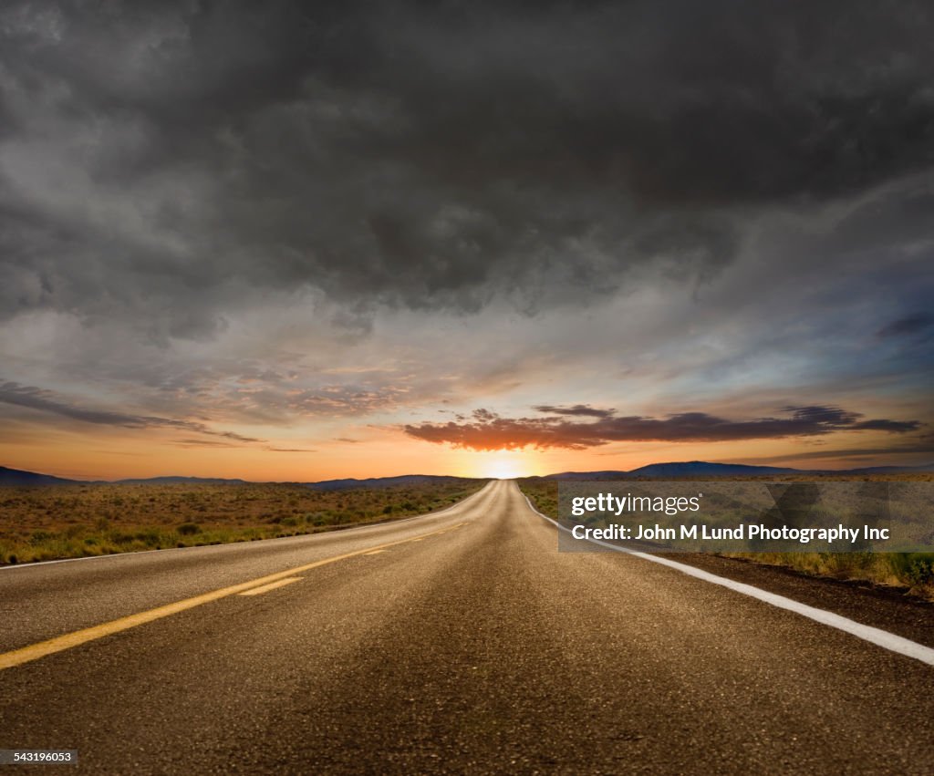 Empty road under sunset sky in remote landscape