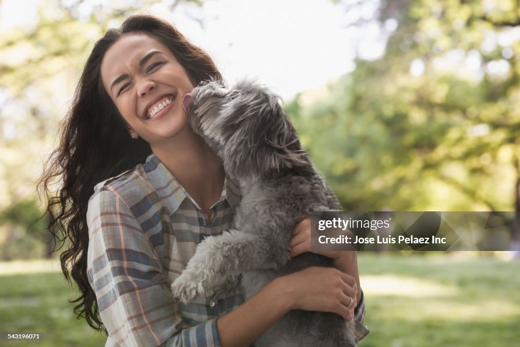 Mixed race woman playing with dog in park