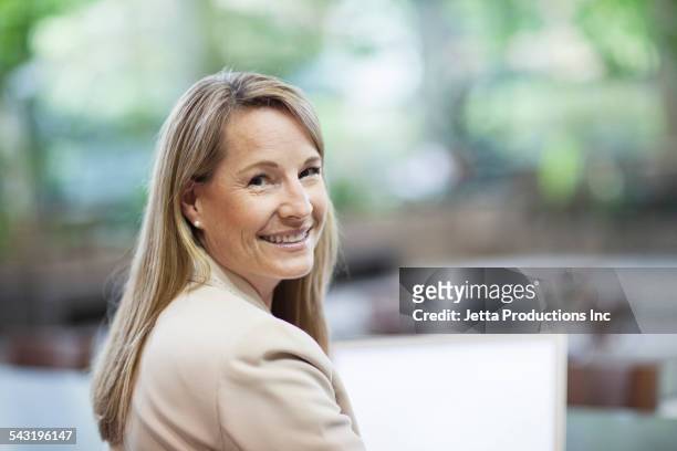 caucasian businesswoman smiling - woman looking over shoulder stock-fotos und bilder