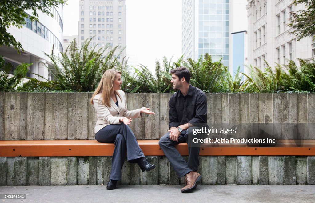Caucasian business people talking on bench outdoors