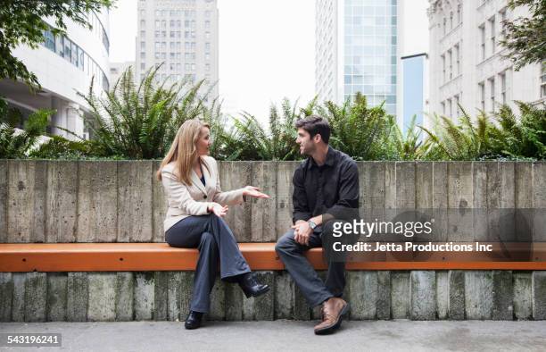 caucasian business people talking on bench outdoors - bench stockfoto's en -beelden