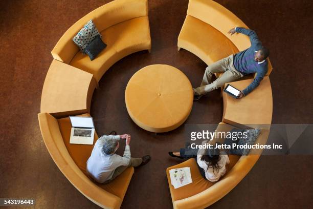 overhead view of business people talking on circular sofa - people technology connected overhead foto e immagini stock