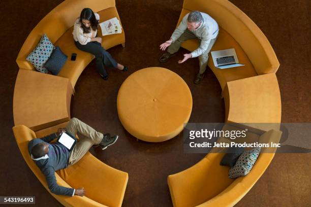 high angle view of business people talking on circular sofa - ict mobiles stock-fotos und bilder