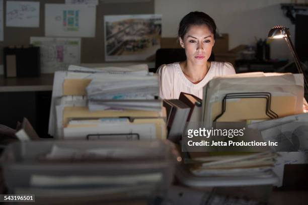 mixed race businesswoman working late in office - working late foto e immagini stock