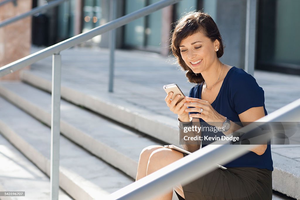 Caucasian businesswoman using cell phone on staircase