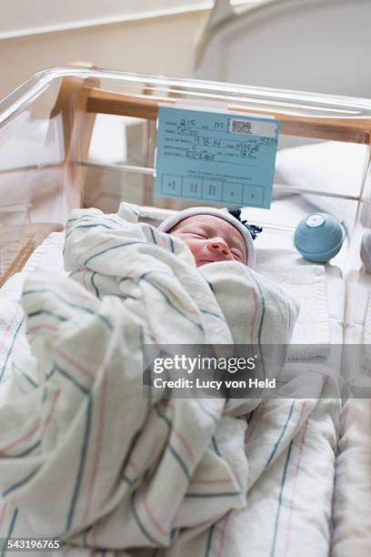 mixed race wrapped in blanket in hospital crib - lettino ospedale foto e immagini stock