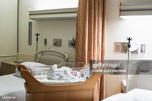 mixed race wrapped in blanket in hospital crib - service de maternité photos et images de collection