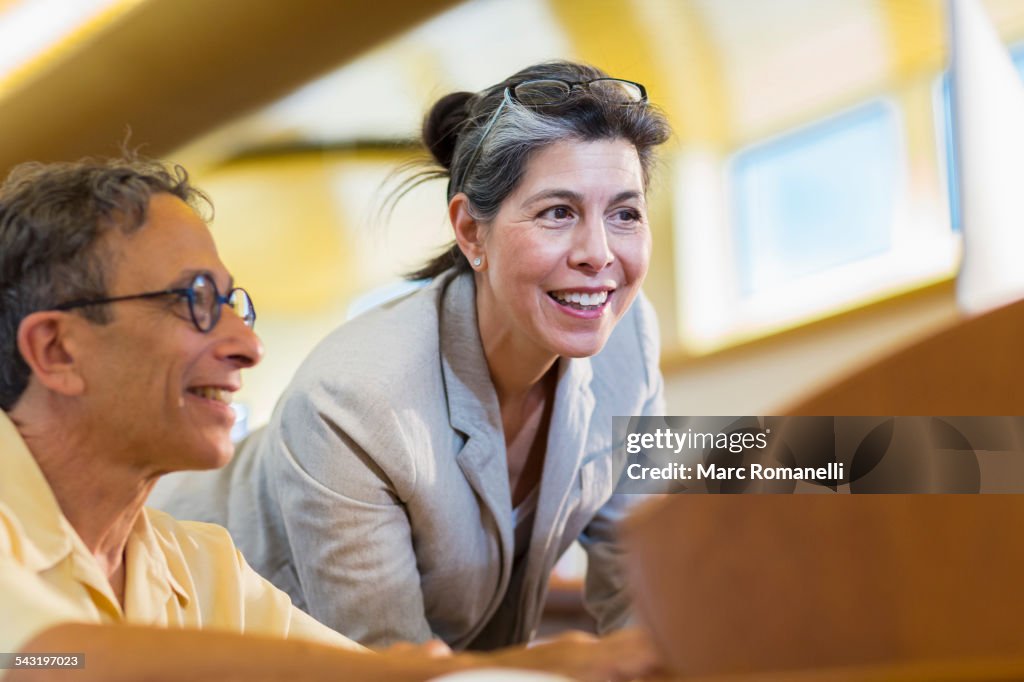 Teacher helping adult student use computer in library