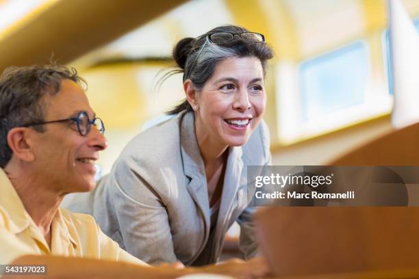 teacher helping adult student use computer in library - bibliotecário imagens e fotografias de stock