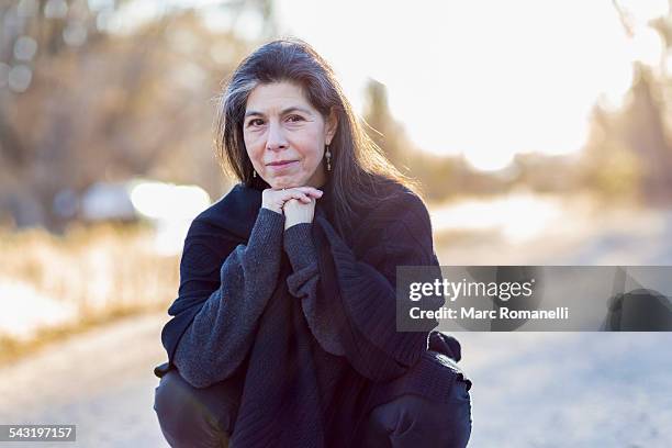 older hispanic woman crouching outdoors - 55 59 years stock pictures, royalty-free photos & images