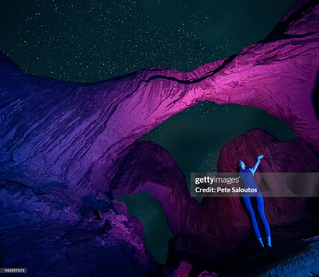 Woman standing in illuminated rocks at night in Arches National Park, Moab, Utah, United States