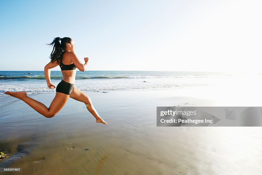 Mixed race woman running on beach