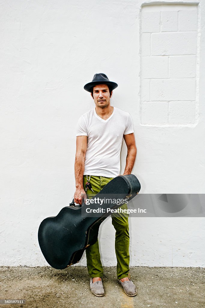 Mixed race musician carrying guitar case