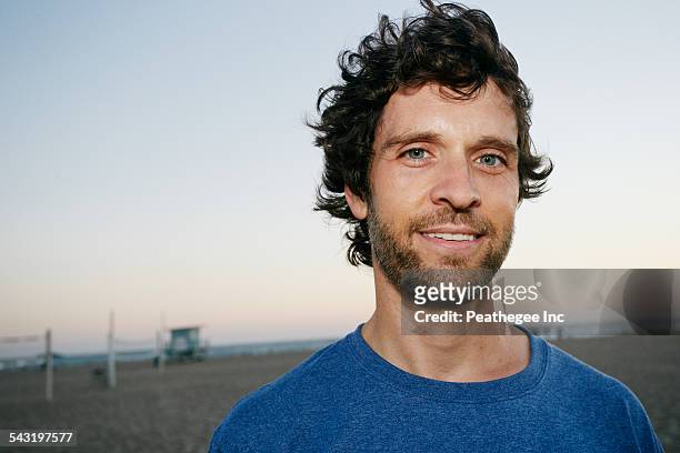 caucasian man smiling on beach - schwarzes haar stock-fotos und bilder