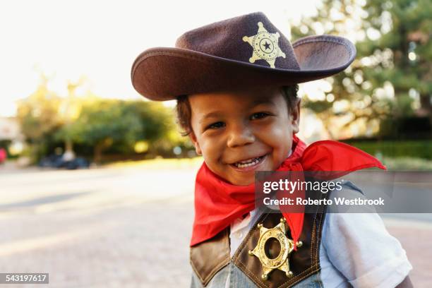 mixed race boy in cowboy costume smiling outdoors - police hat stock pictures, royalty-free photos & images