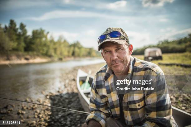 caucasian man sitting in canoe on riverbed - fischer männlich stock-fotos und bilder
