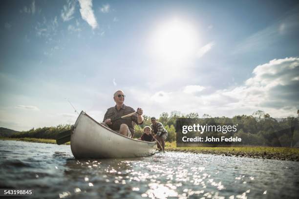 three generations of caucasian men paddling canoe in river - región central de eeuu fotografías e imágenes de stock