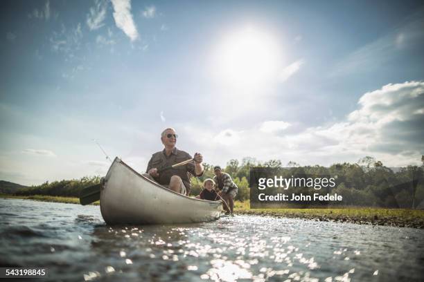 three generations of caucasian men paddling canoe in river - boat river stockfoto's en -beelden