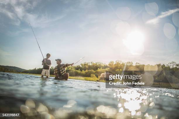 caucasian father and son fishing in river - かがむ 人 横 ストックフォトと画像