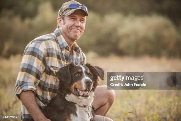 caucasian man petting dog in rural field - only mature men fotografías e imágenes de stock