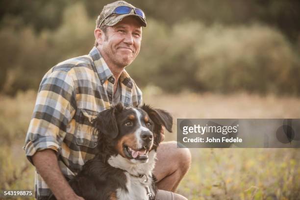 caucasian man petting dog in rural field - 中年の男性だけ ストックフォトと画像