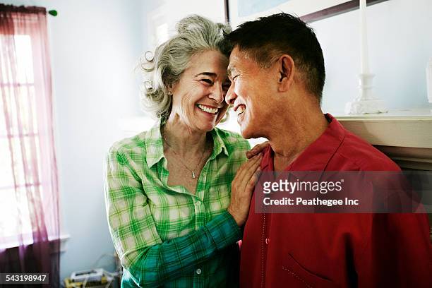 smiling couple hugging in living room - asian senior couple stock pictures, royalty-free photos & images