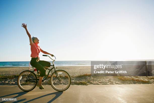 caucasian woman riding bicycle near beach - old woman side view foto e immagini stock