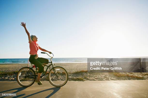 caucasian woman riding bicycle near beach - bike beach stockfoto's en -beelden