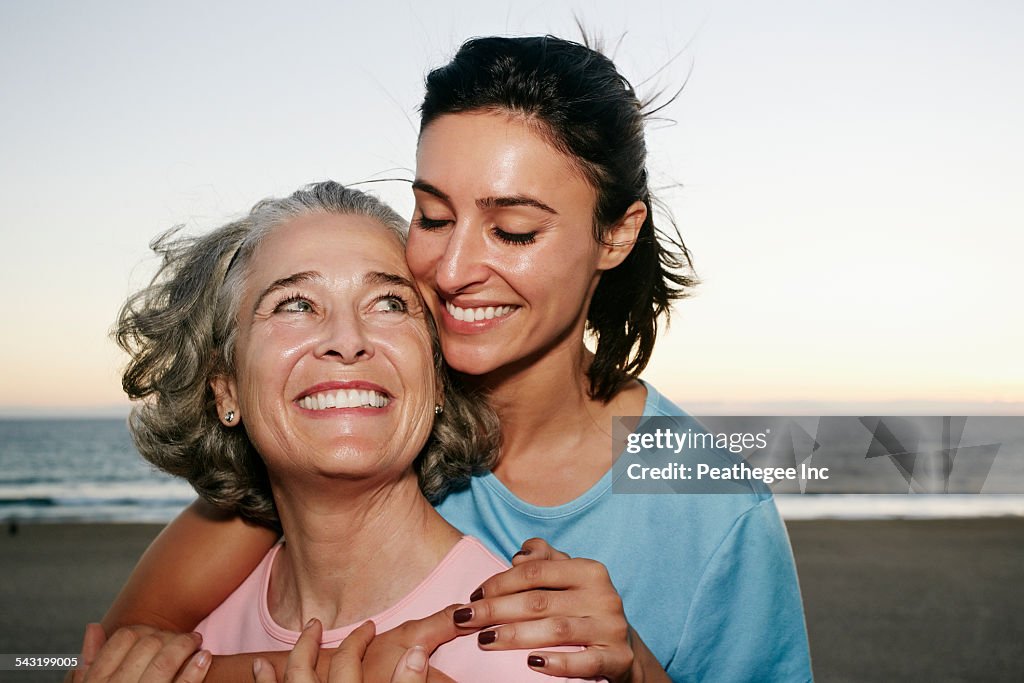 Caucasian mother and daughter hugging at beach