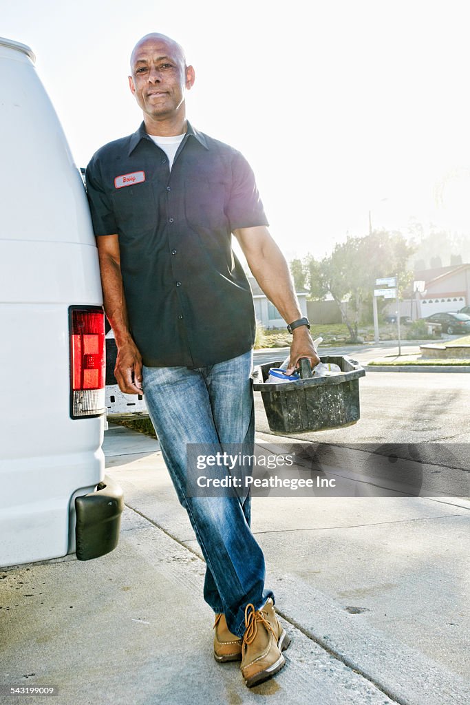 Mixed race plumber holding tools van