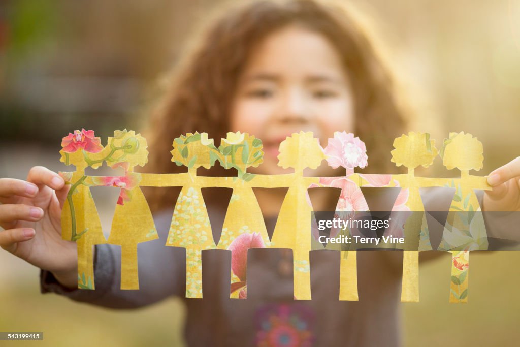 Mixed race girl holding row of paper dolls