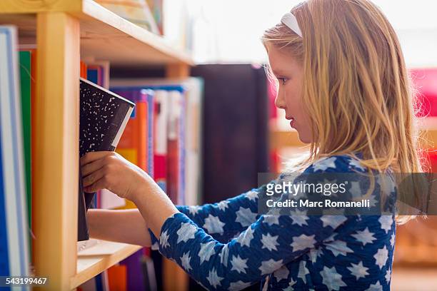 caucasian girl selecting book in library - choosing a book stock pictures, royalty-free photos & images