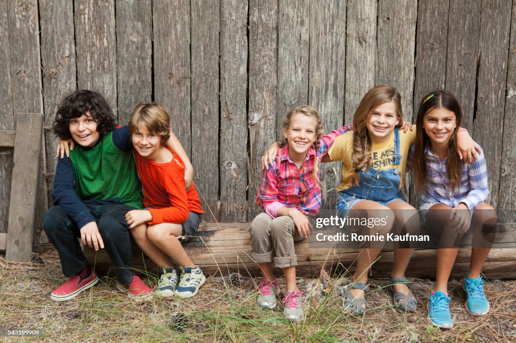 Caucasian children smiling together on wooden log