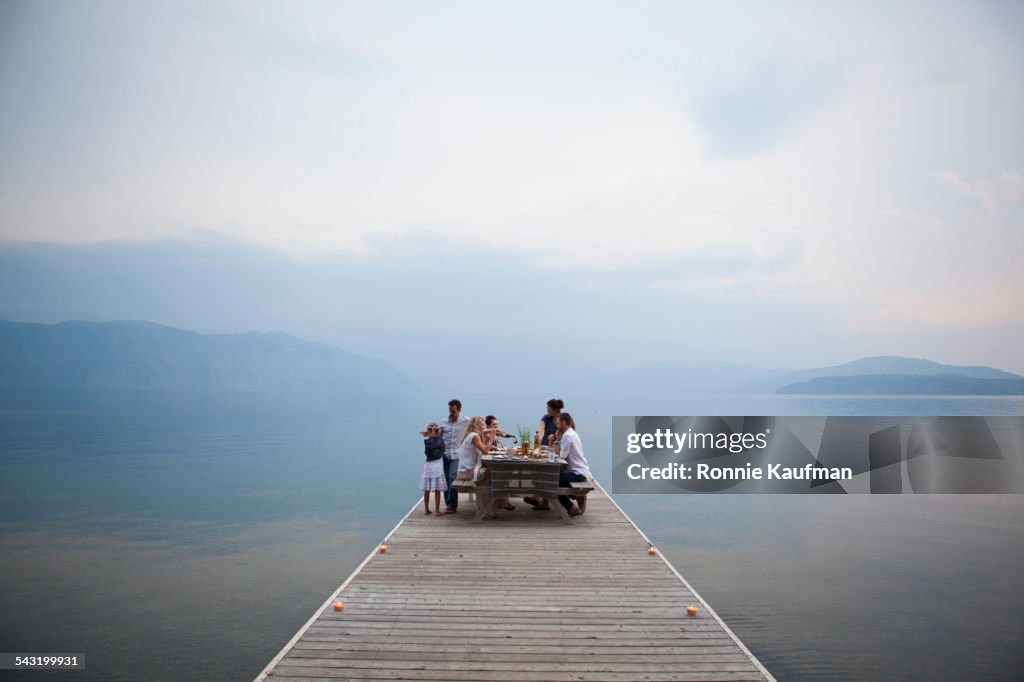 Caucasian family at picnic table on wooden dock over lake