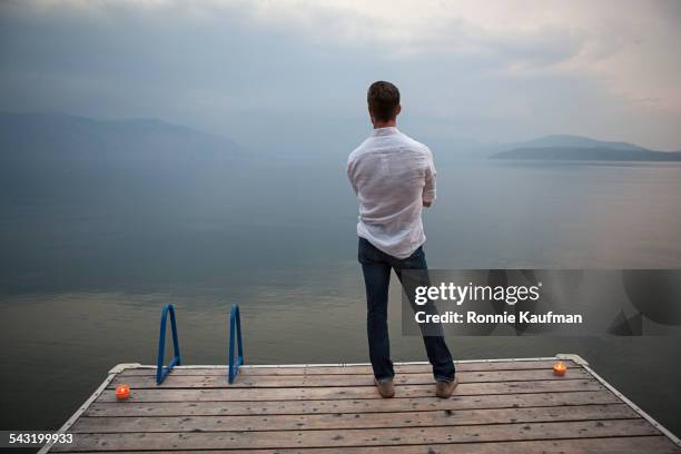 caucasian man standing on wooden dock over lake - dos photos et images de collection