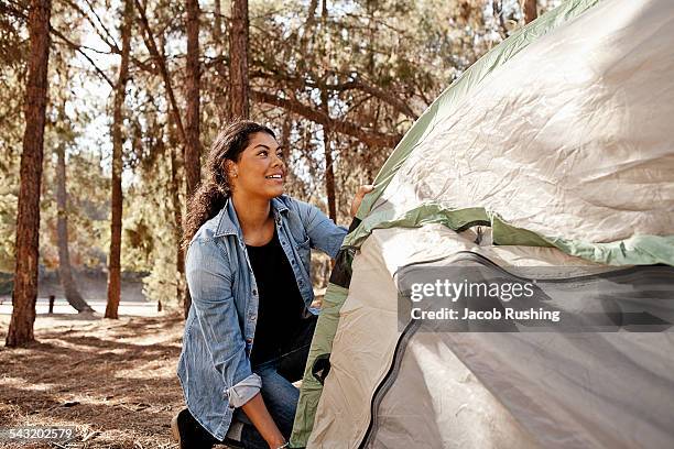 young woman in forest putting up tent - concentration camp photos photos et images de collection