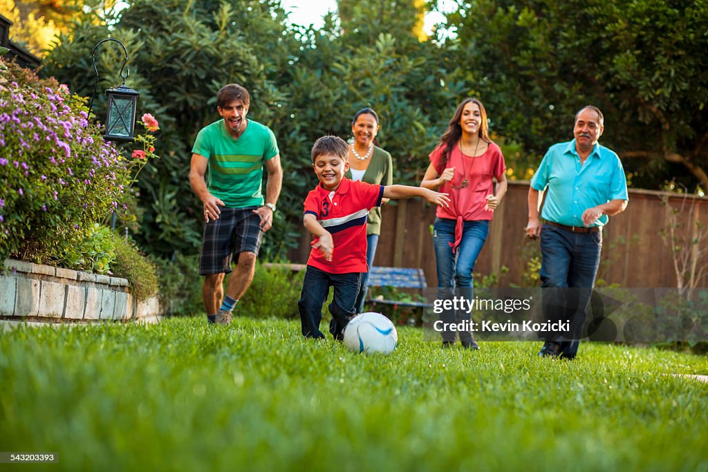 Three generation family playing football in garden