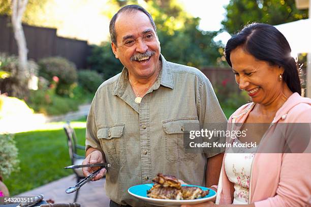 husband and wife at barbecue grill in garden - rancho palos verdes stock-fotos und bilder