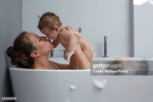 mother and baby girl in bathtub - bañando bebe fotografías e imágenes de stock