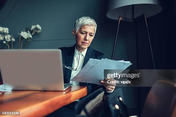 mature businesswoman in her office. - reading document stock pictures, royalty-free photos & images